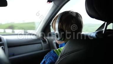 家庭旅行。 <strong>一家人</strong>在公路上<strong>开车</strong>。 少年坐在车里，通过耳机听音乐