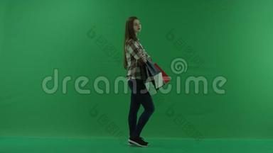 女孩站在她的右边，把她的袋子放在她弯曲的<strong>胳膊</strong>肘上，在绿色的屏幕上等待什么东西