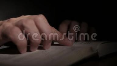 特写一个人`手拿着一本打开的纸书，用手指翻页