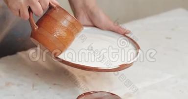 熟练的陶工釉从红泥中覆盖盘子。 关<strong>上门</strong>。 进程。 陶瓷车间。