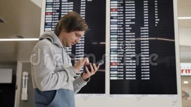 旅行者在机场使用智能手机。 年轻的白种人旅行者用手机应用程序检查登机时间。