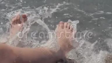 一个孩子的腿`特写被波浪淹没了。 卵石沙滩<strong>喧闹</strong>的海浪拍打着孩子们`双腿
