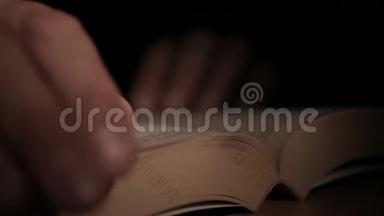 特写一个人`手拿着一本打开的纸书，用手指<strong>翻页</strong>