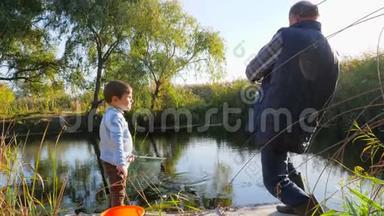 夏天在湖边钓鱼，爷爷带着孙子在温暖的天气里享受大自然的美好时光