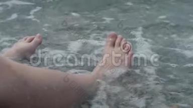 一个孩子的腿`特写被波浪淹没了。 卵石沙滩<strong>喧闹</strong>的海浪拍打着孩子们`双腿
