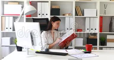 穿白色衬衫的女商人在文件夹里检查文件。