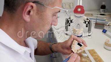 牙科技师用刷子将白色粉末涂在陶瓷牙齿上，然后插入专用仪器