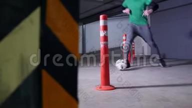 地下停车场。 一个足球运动员训练他的足球技能。 带球穿过障碍物