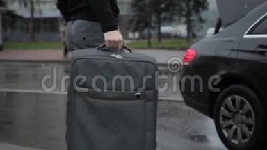 人在汽车后备箱里装着带手柄的大型手提箱。