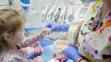 口腔科医生为儿童在牙椅上展示工具，并在模型颌骨特写上教授刷牙