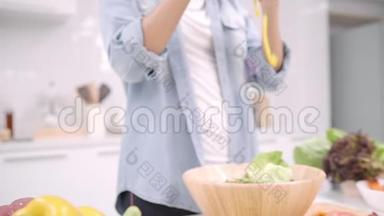 慢动作-年轻的亚洲女人在厨房里做沙拉健康食品，漂亮的女人在随意使用有机食品。