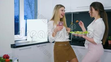 有用的食物，快乐的女朋友在厨房午餐时在android上看照片