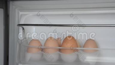 一个人从<strong>冰箱</strong>的架子上拿了两个<strong>鸡蛋</strong>
