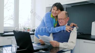 网上购物快乐的老年夫妇用笔记本电脑<strong>在线支付</strong>，享受商业上的成功，并拥抱在。
