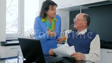 养老金领取者的家庭事务，老妇人和丈夫一起发誓坐在手提电脑后面拿着文件