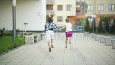 两个快乐的孩子手拉手一起跑。 他们的金发在风中飘扬.