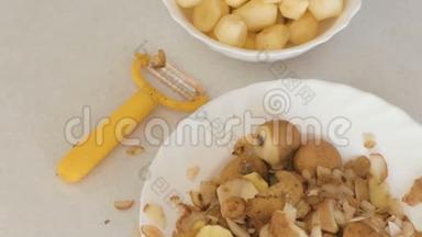 盘子里的小土豆，厨房桌子上的果皮和剥皮机。 上景。
