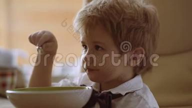 小男孩在享受他的粥。 有趣的孩子吃牛奶粥。 婴儿<strong>食品</strong>，婴儿<strong>食品</strong>