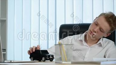 年轻的商人在办公室的桌子上玩一辆<strong>小汽车</strong>。 慢动作