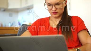一个穿红色衣服的女人在笔记本显示器<strong>后面</strong>工作的肖像。 美玲，女自由职业者，秘书，办公室职员