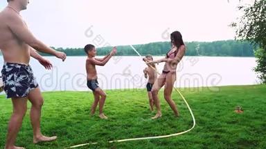 母亲带着父亲和两个孩子在<strong>草坪</strong>上玩耍，倒着水，笑着在<strong>操场</strong>上玩