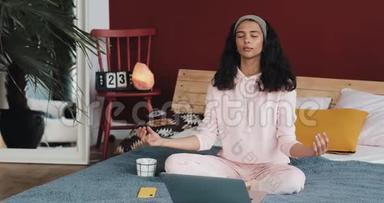 美丽的年轻非洲裔美国妇女在家做瑜伽运动，在笔记本电脑上看教程