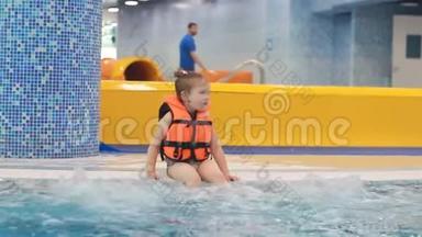 泳池里穿着救生衣的小女孩坐在沸腾的蓝色水中，正准备潜水
