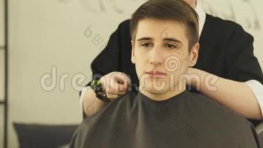 女理发师在理发室理发前，穿着紧身长袍的年轻人。 在理发店理发