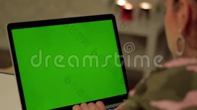 穿<strong>迷彩服</strong>的女孩在带绿色屏幕的笔记本电脑上工作