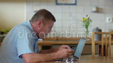 退休年龄的人使用笔记本电脑和电话。 他仔细地看着电脑屏幕，眯<strong>着眼</strong>睛，戴<strong>着眼</strong>镜