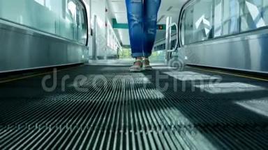 穿凉鞋的女人腿站在自动人行道上，站在地铁地铁站的自动扶梯上