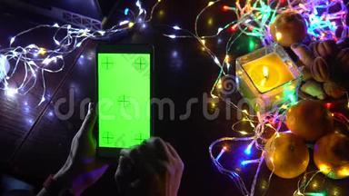 使用智能手机手在黑色背景桌子与彩色灯，圣诞节新年作文。 智能手机游戏