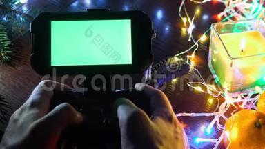 使用手游戏垫与智能手机在黑色桌子与彩色灯，圣诞节新年作文。 智能手机游戏