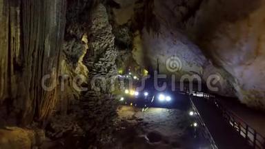 在巨大的喀斯特洞穴中通过桥梁接近彩色灯具的运动