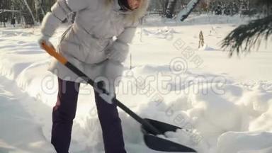 年轻女子在冬天用铲子铲雪。