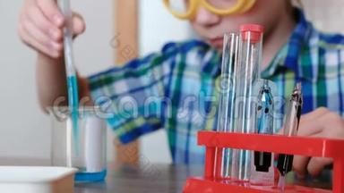 家庭化学实验。 男孩用吸管从烧<strong>杯中倒入</strong>蓝色液体到试管中。