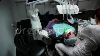 一个女人拿着一个<strong>牙医</strong>在<strong>牙医</strong>`办公室里钻孔病人的牙齿，并用栅栏把牙齿的残余物围起来。