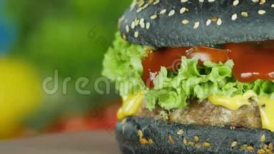 夹着牛肉的汉堡和一个黑色的面包夹在一块木板上的生菜叶和蔬菜的模糊背景上