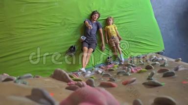 一个年轻的攀岩教练教小男孩如何在一个巨石攀岩馆里爬墙