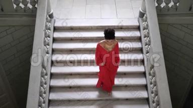 俯视图上，穿着别致红色长裙的女子高跟鞋走下一个大楼梯