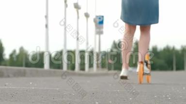 漂亮的年轻女子，穿着<strong>牛仔裙</strong>，穿着白色运动鞋，骑着一辆踢踏车穿过街道。