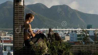 女孩坐在盆栽的露台墙上打电话
