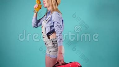 漂亮的女孩拿着一个红色的手提箱，喝橙汁。 女孩在旅<strong>途中</strong>飞翔