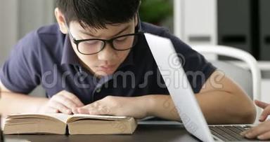 亚洲十几岁男孩提<strong>防眼镜</strong>，在家里用笔记本电脑，可爱的男孩认真地做作业。