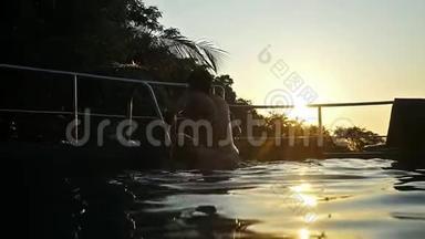 年轻人在夕阳下的游泳池里跳着，水在夕阳下翻滚，水在美丽的波克中飞溅