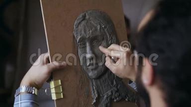 雕塑家的特写镜头在艺术工作室的画布上创作人`的面部雕塑