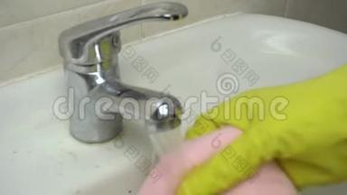 手里拿着黄色的橡胶手套，用抹布用清洁剂清<strong>洗浴</strong>室水槽