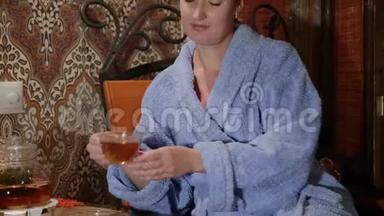穿着浴袍的漂亮女孩喝茶。