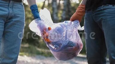两名志愿者在<strong>清理</strong>森林后拿出<strong>垃圾</strong>和回收塑料瓶