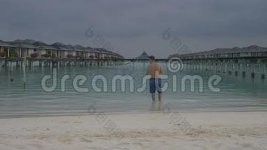 <strong>一个人走</strong>进海洋，站在水上别墅前.. 马尔代夫的白色沙滩。